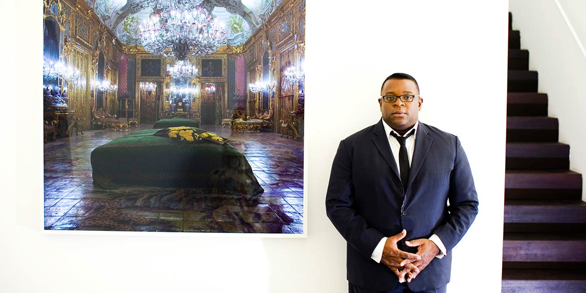 Isaac Julien stands next to a painting.