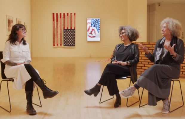 A group of people sit and have a conversation in an art exhibit.