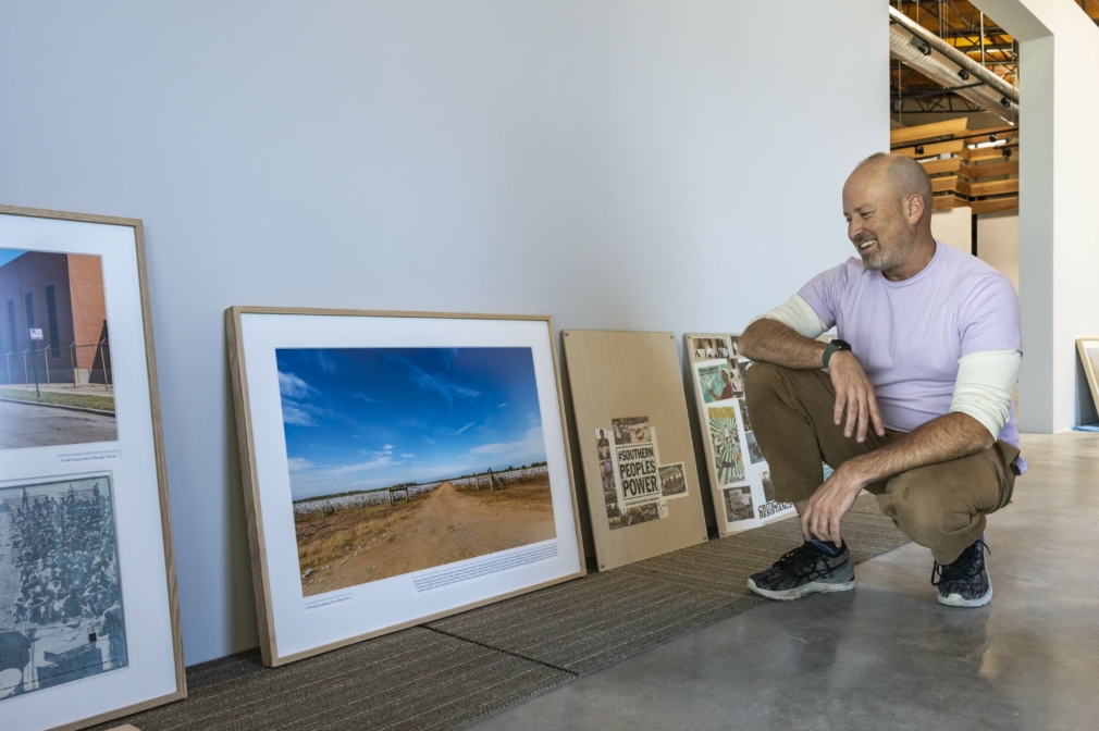Person squats on the floor next to framed photographs