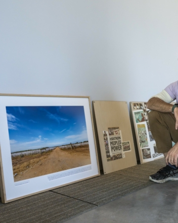 Person squats on the floor next to framed photographs
