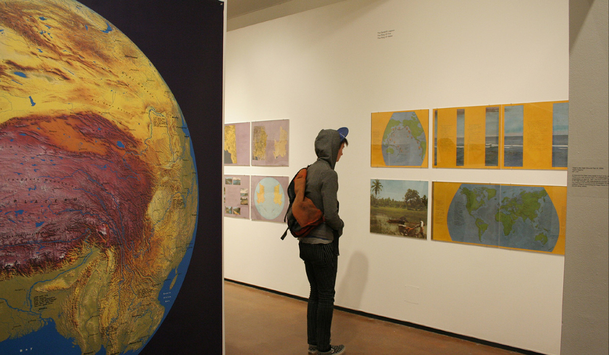 A student looks at art depicting the globe in an exhibit.