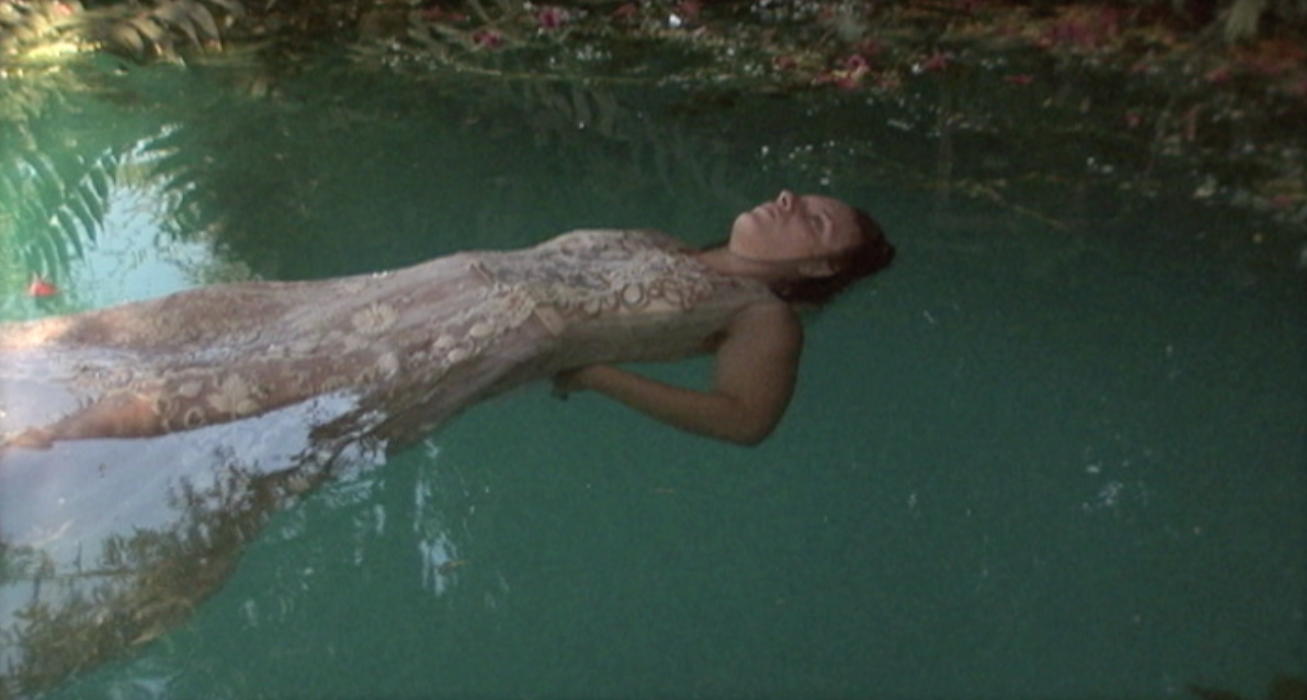 A person in a dress floats on their back in water.