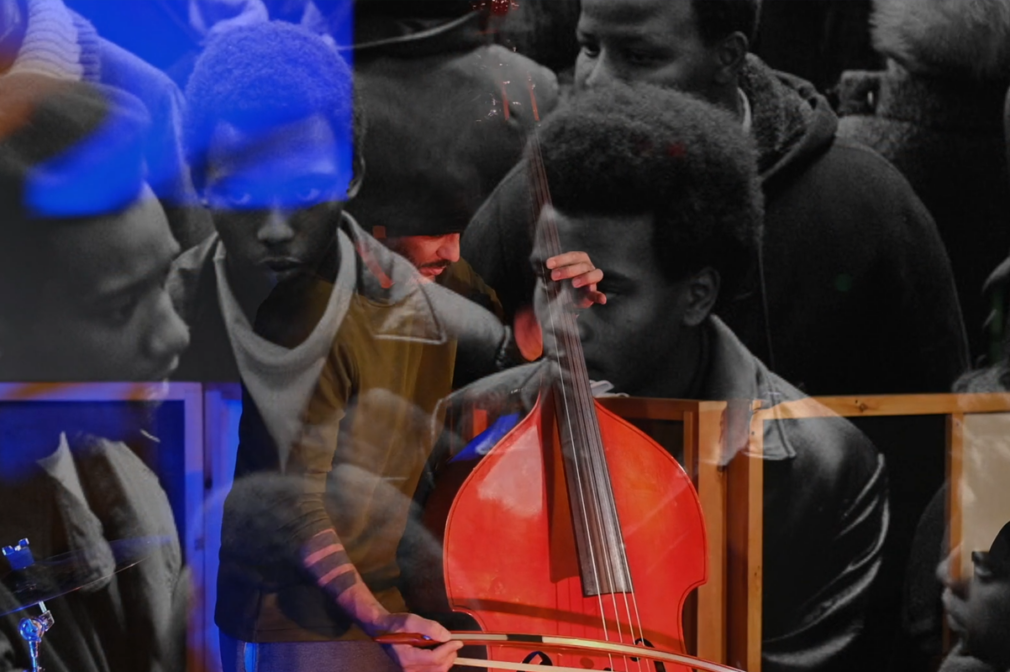 A man plays a cello while historical footage is overlaid over him.