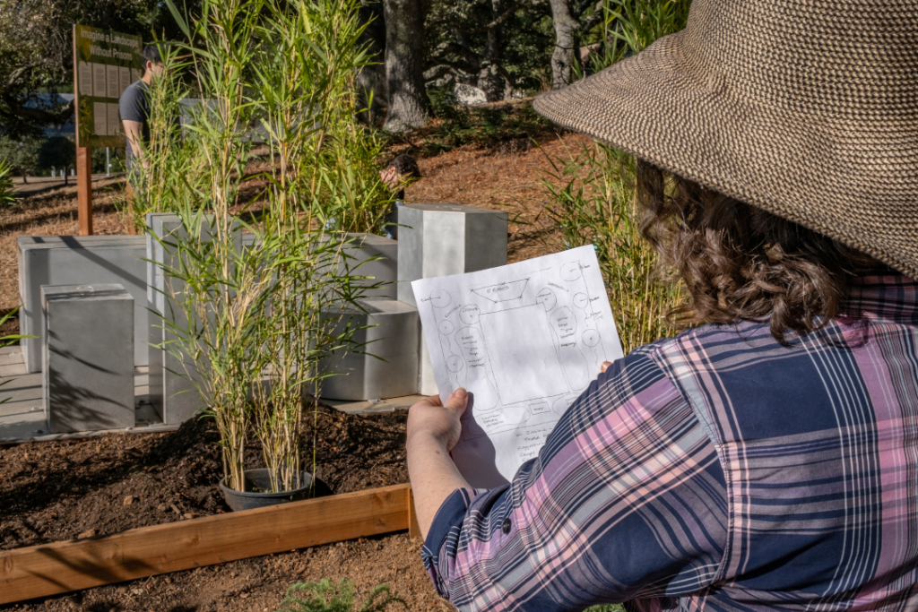 A woman looks at a blueprint of the garden while a student looks on in the background.