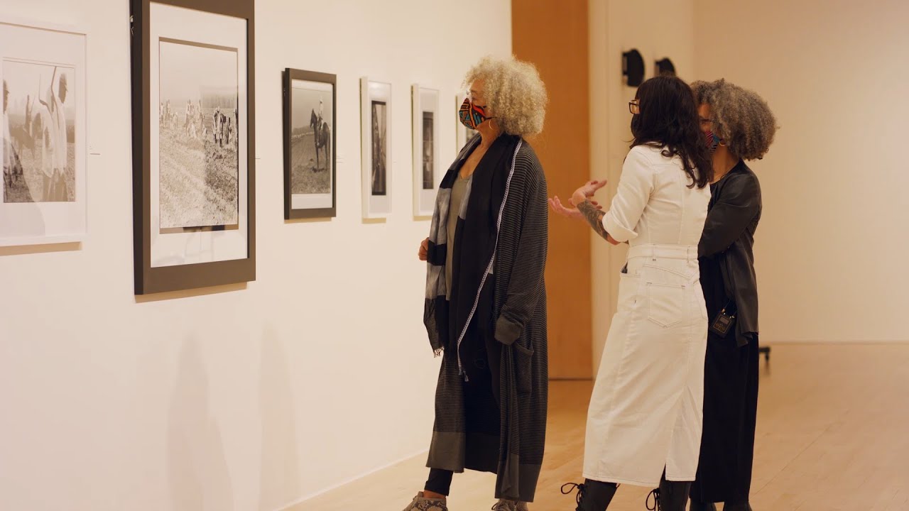 Three women looking at black and white photographs of the Louisiana State Penitentiary 