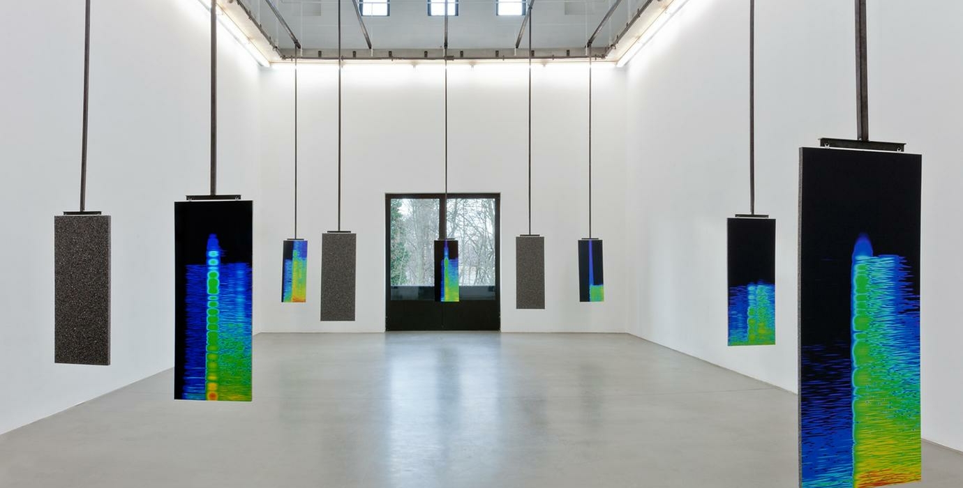 Installation of multiple screens hanging from the ceiling of an art gallery