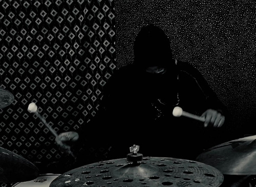 A drummer performs in a dark space.